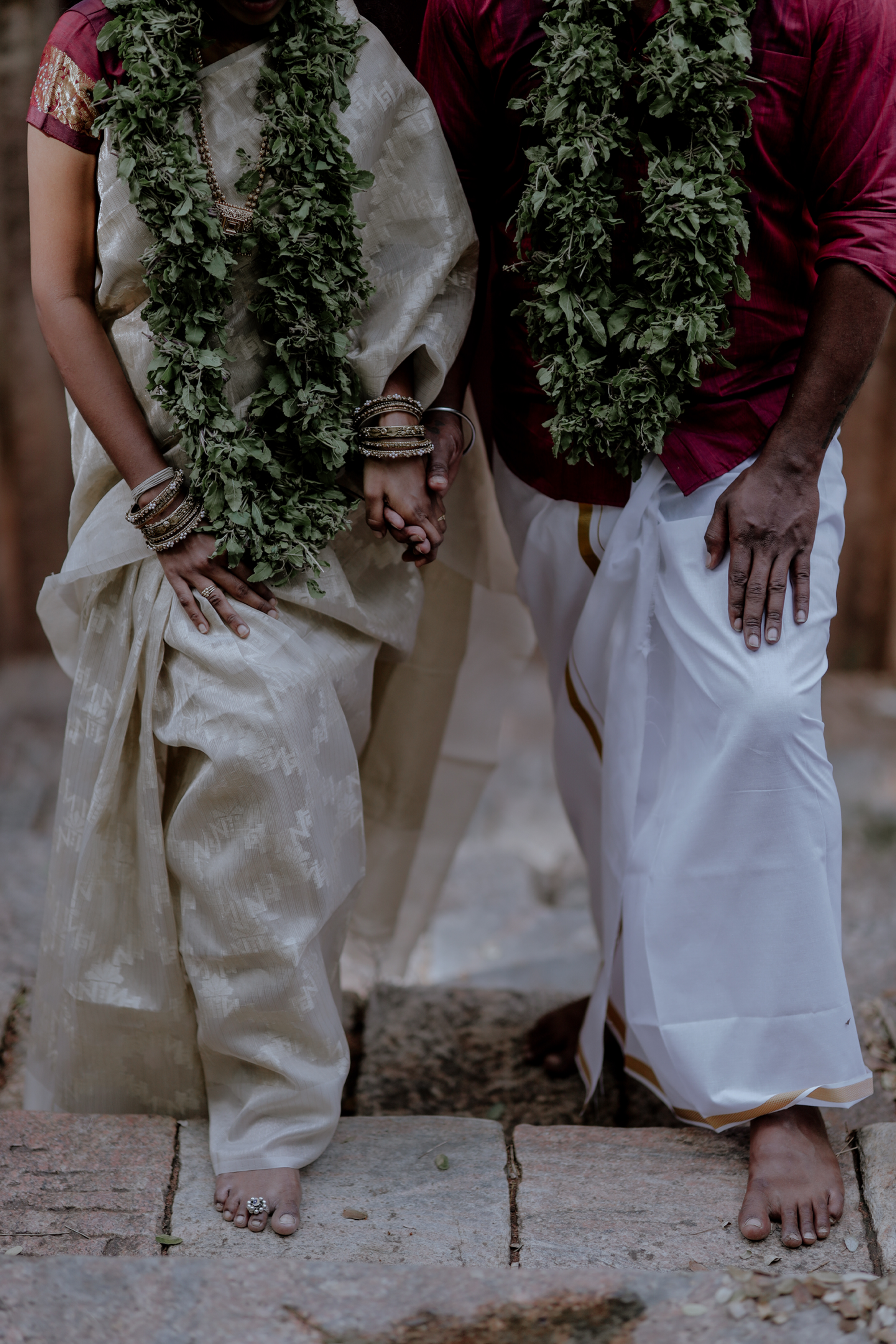Wedding couple holding hands with garlands